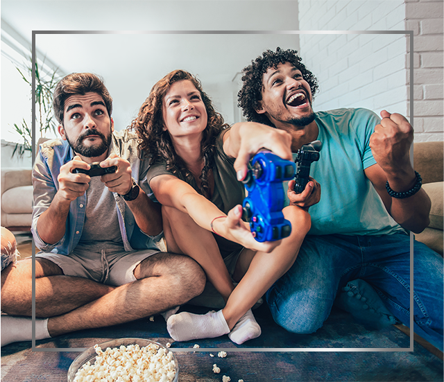 Grupo de jovens sorridentes sentados no chão, brincando de videogame, felizes após o tratamento de infecção da pele por fungos Canesten