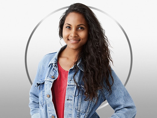 Mulher jovem sorridente de cabelo escuro, vestindo uma camiseta vermelha e jaqueta jeans, feliz após o tratamento para dermatofitose Canesten