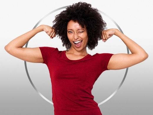 Mulher jovem sorridente, com cabelo escuro, vestindo camiseta vermelha e braços flexionados